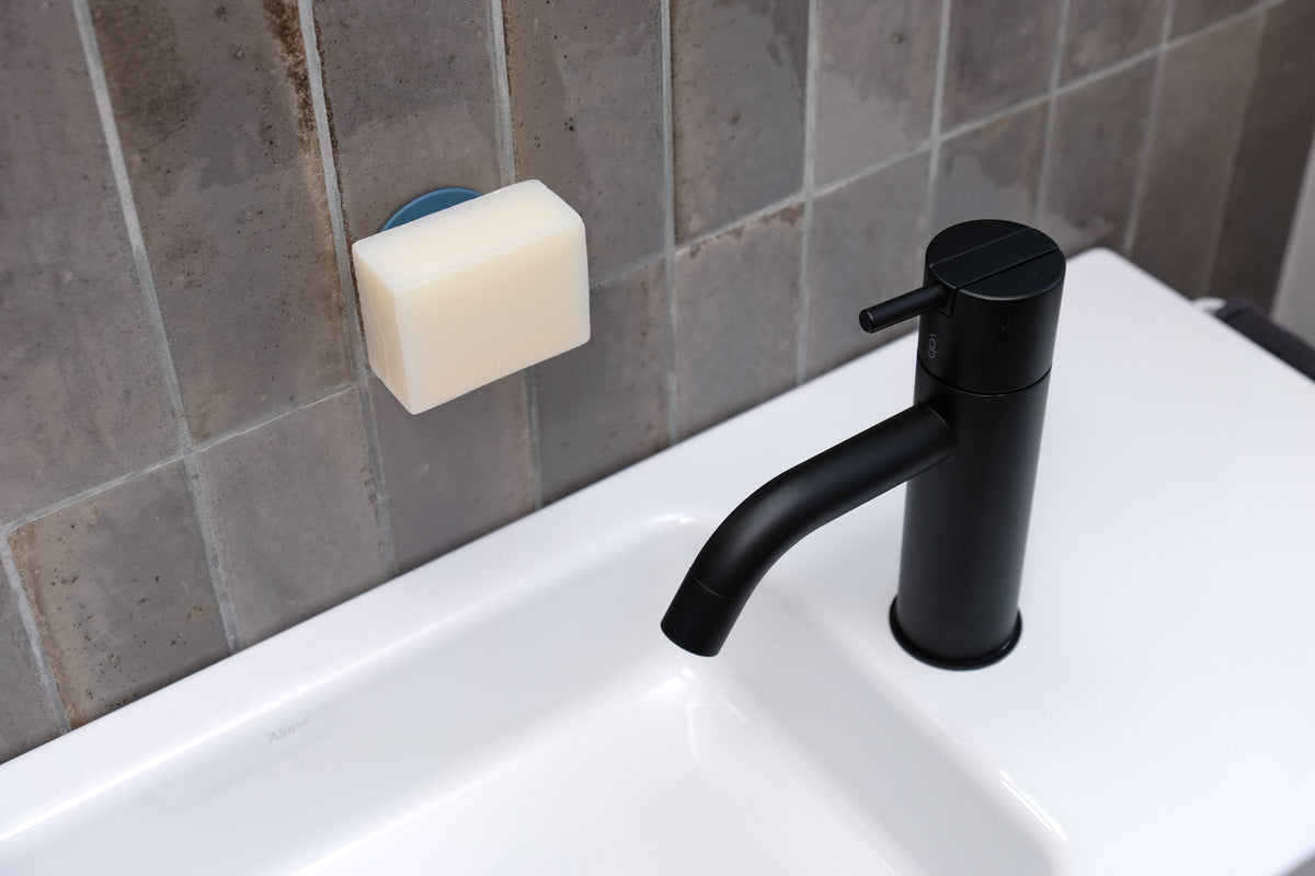 Feste Seife am Soapi über einem weißen Waschbecken mit schwarzem Wasserhahn