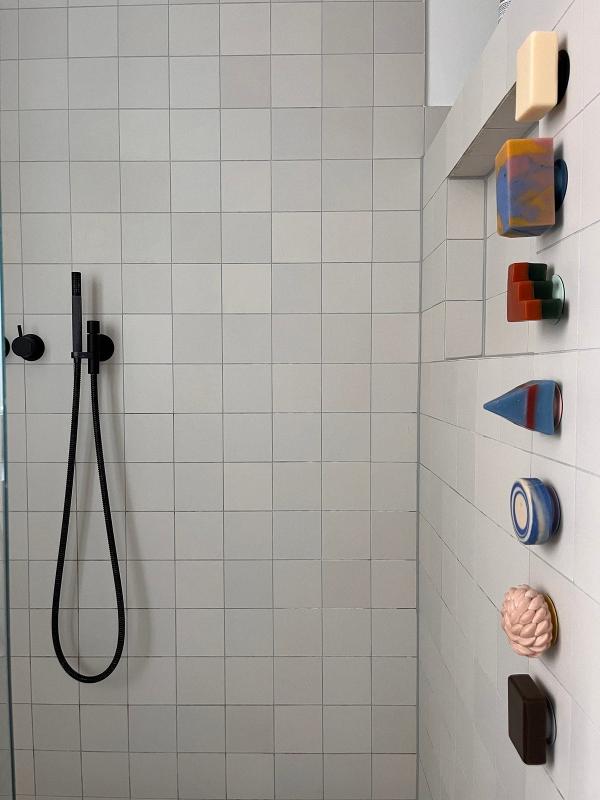 Dusche mit mehreren festen Seifen und Shampoos an magnetischen Seifenhaltern