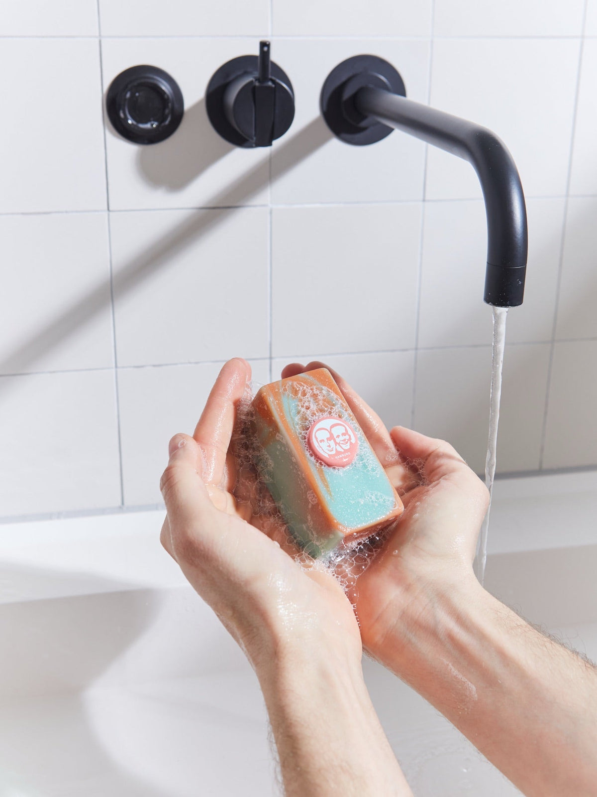 Hände halten ein festes Seifenstück am Waschbecken