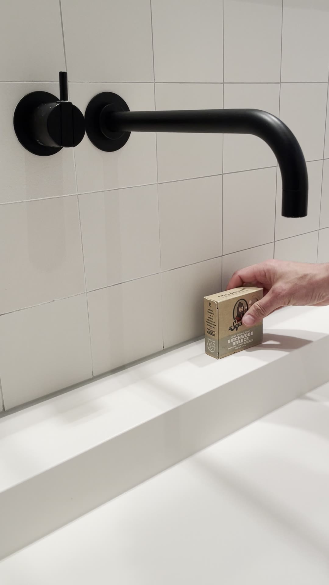 Hand legt ein festes Seifenstück am Waschbecken ab, Idee für kleine Geschenke für Nachbarn
